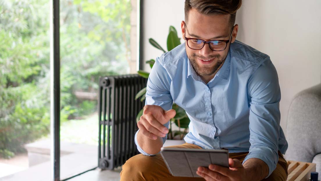 Persoon met bril kijkt glimlachend naar een tablet